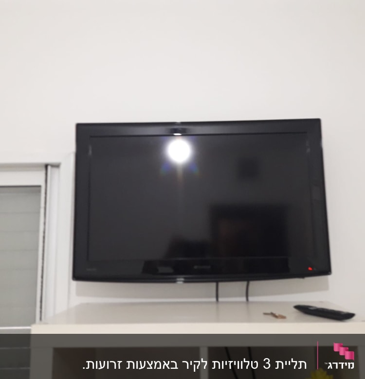 טלוויזיה תלויה על הקיר עם שלט על מדף